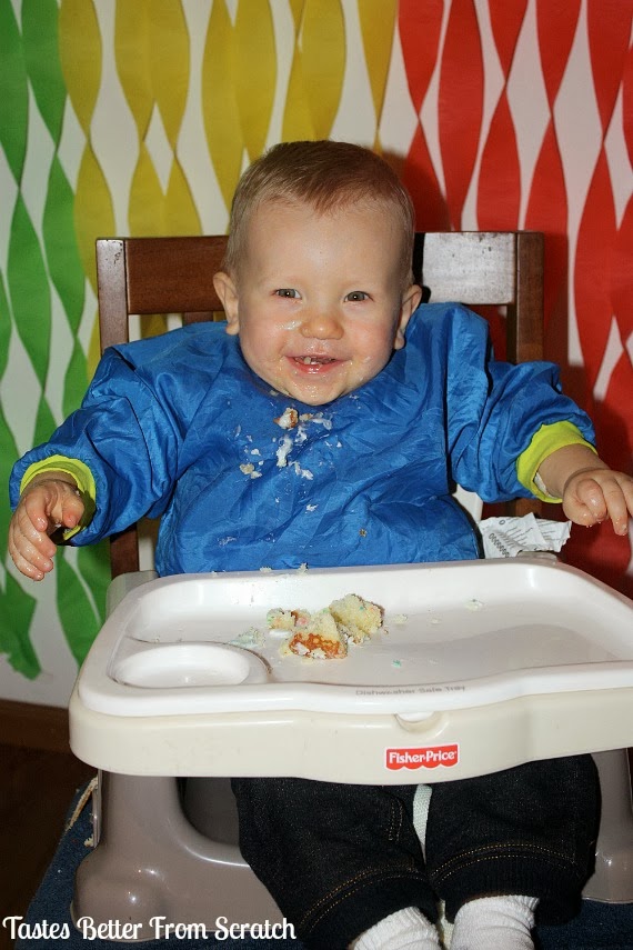 A one year old taking his first bite of cake.