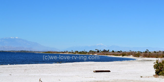 White sand along the beach and snowcapped mountains for background.