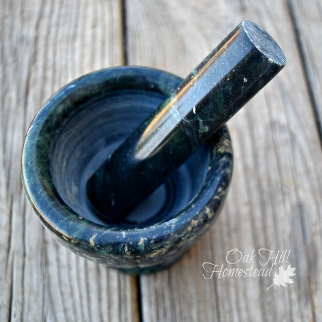 Green marble mortar and pestle on a wooden counter.