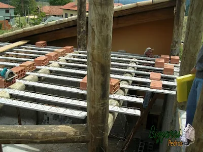 Detalhe da armação da laje do piso em cima das vigas de madeira de eucalipto tratado com os pilares de madeira com a alvenaria de bloco de cimento em construção de sala de estar com a suíte superior em construção rústica no sul de Minas Gerais-MG.
