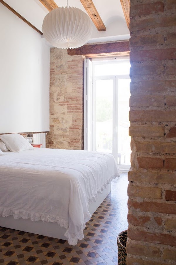 dormitorio con pared de mamposteria y vigas de madera