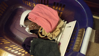 A small pile of bras, pantyhose, and socks in a purple laundry basket