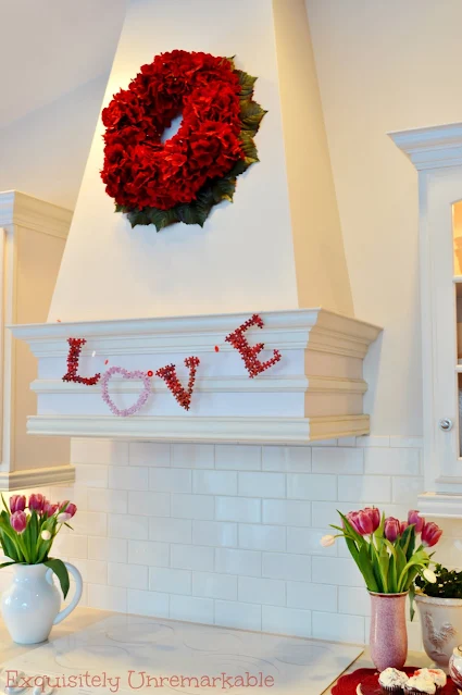 White kitchen hood with Love banner and red wreath on it