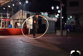 Performer spinning inside a large hoop, night scene, festival