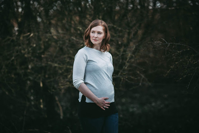 photo shows a pregnant woman standing outside and looking off camera