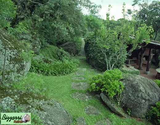 Caminho com pedras rústicas chapada que sai da residência e vai até a construção da churrasqueira com execução do paisagismo natural.