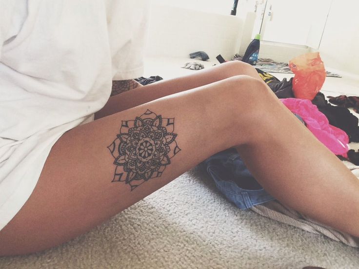 chica sentada en alfombra con tatuaje de mndala en pierna