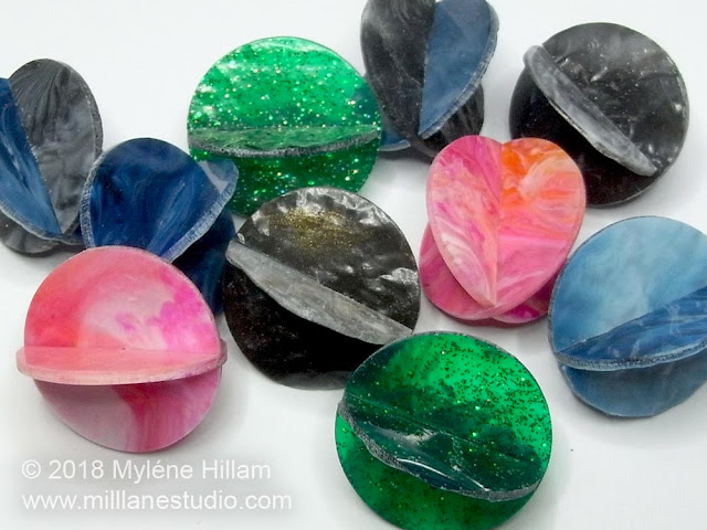Marbled resin circle beads in blue, black, pink and green.
