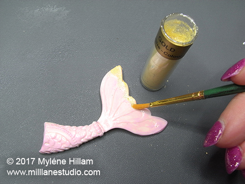 Adding edible gold dust highlights to the tips of the mermaid's tail.