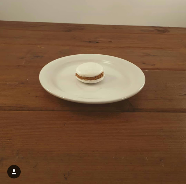 Salted Caramel macaron on a while plate with a wooden table background