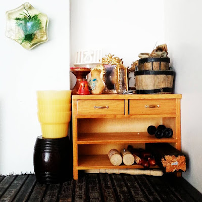 Corner of a one-twelfth scale industrial-style miniature artist's studio, with a workbench holding various old wooden pieces.