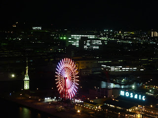 Ferris wheel lit up with pink lights in Harbour land as seen from the top of the Kobe Port tower at night