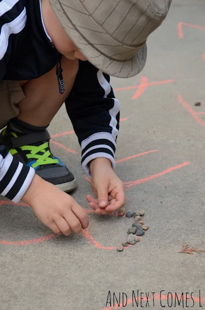 Child tracing letters with rocks outdoors