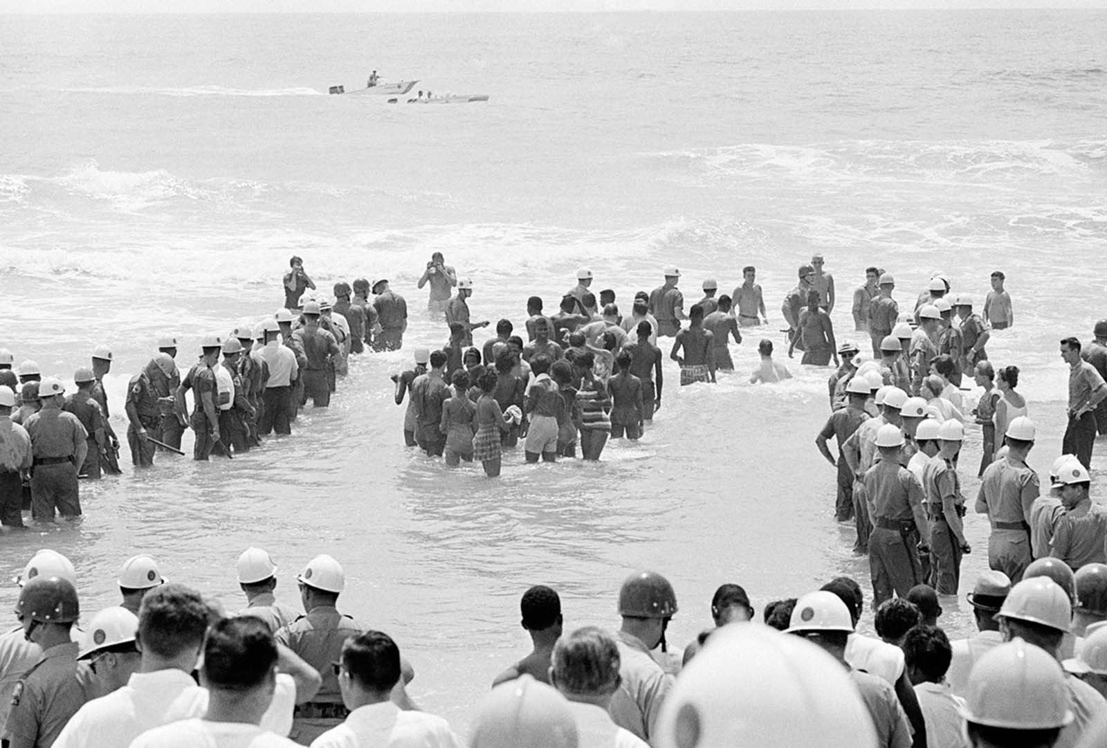 A group of African American and white demonstrators are guarded by a heavy surrounding force of police officers, during a wade-in at St. Augustine Beach, Florida, on June 29, 1964. Only a few segregationists were on hand and there were no incidents.