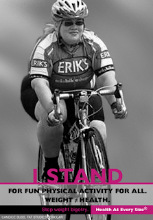 Author on a bicycle in cycling attire & helmet, on a road bike. Photo is black & white, with pink text saying "I stand" and black text saying "for fun physical activity for all. Weight =/= health"