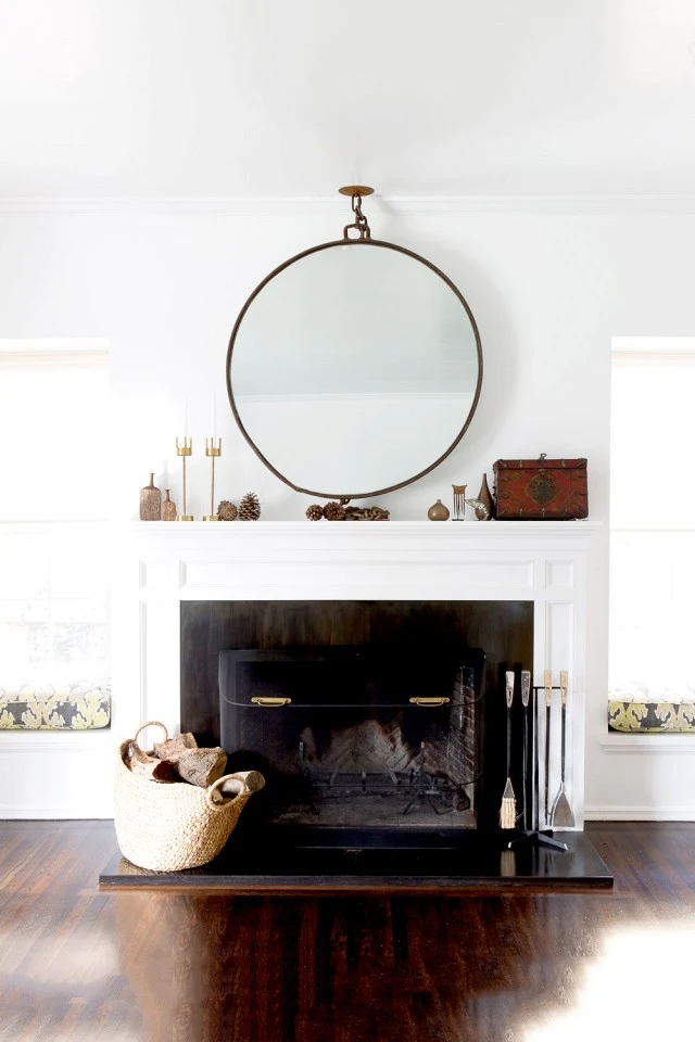 round statement mirror over fireplace