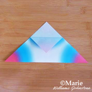 Folding back tip of triangle on paper