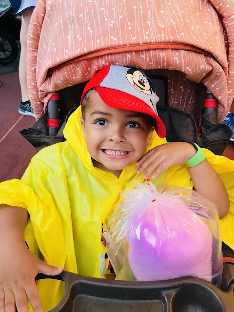 Little boy in mickey mouse baseball hat and mickey mouse poncho at walt disney world
