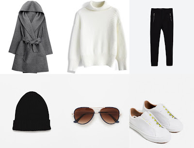 casaco comprido cinzento claro, calças pretas. tênis brancos, óculos de sol em massa e gorro preto 