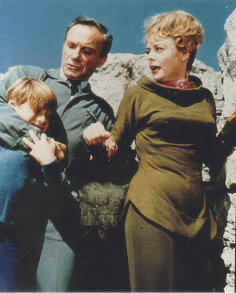 Dr. Smith holding Will tight while Maureen Robinson looks on in http://movieloversreviews.blogspot.com