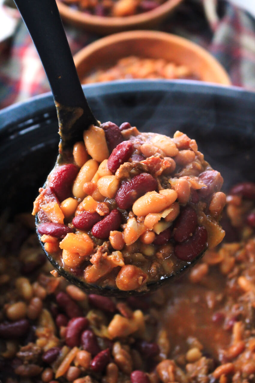 A large ladle overflowing with Cowboy Beans.