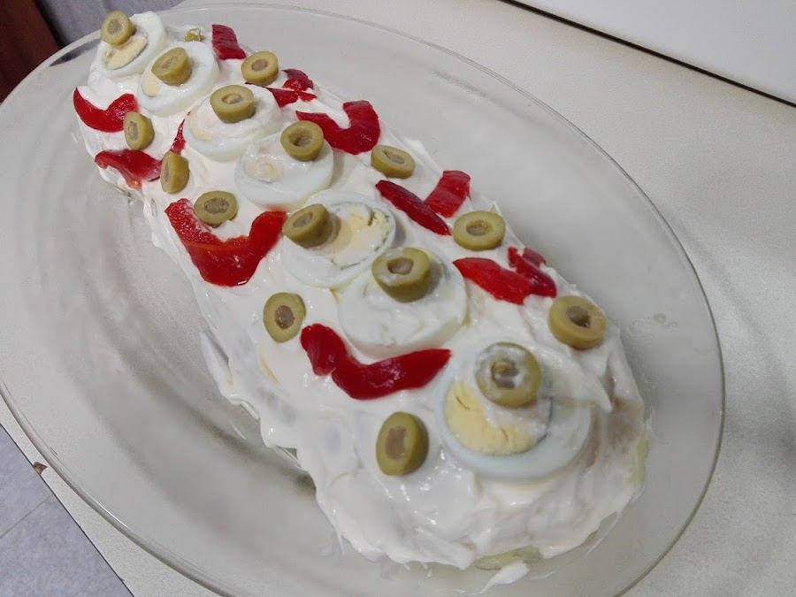 Rollo de patata relleno, cubierto de mayonesa y adornado en una fuente