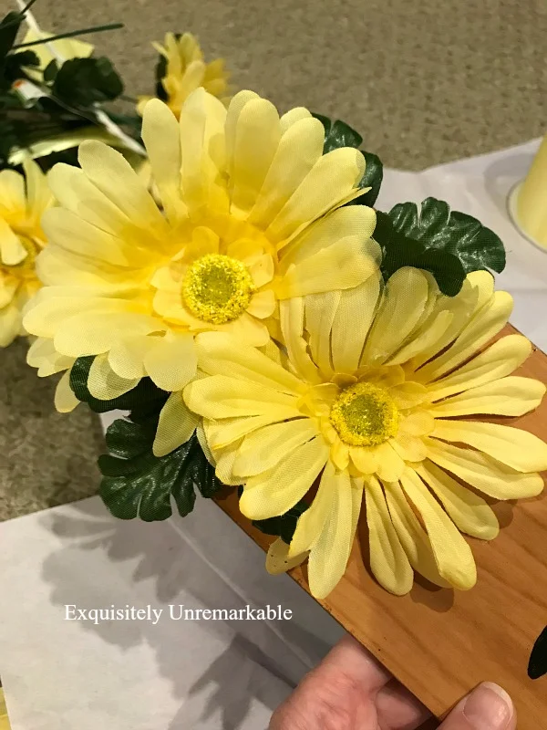 Yellow flowers and greenery glued to wooden fan blade