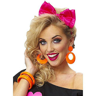 Girl wearing orange plastic hoop earrings, orange plastic bangles and pink hair bow