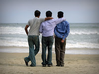 Birbirlerinin omuzlarına ellerini koyarak denizi izleyen üç erkek arkadaş