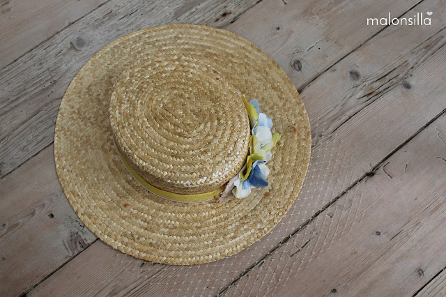 Sombrero de paja con flores para boda sobre suelo de madera.