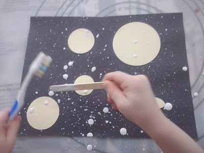 toddler making a space scene using splatter painting