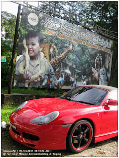 gambar kereta sport berwarna merah dengan latar belakang papan tanda Zoo Taiping Night Safari