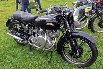 Powerful black motorcycle on display on grass.