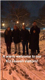 A photo of people in winter coats standing on the snow-covered quad after dark. A caption over the image reads, "A warm welcome to our KU Leuven visitors!".