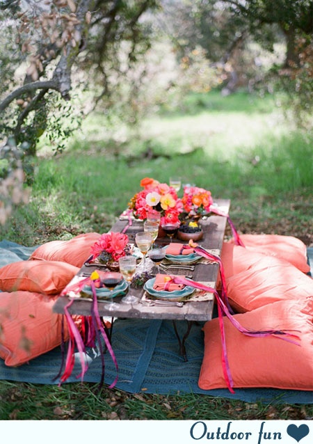 This adorable outdoor picnic set up with flowers and colorful decor is adorable.