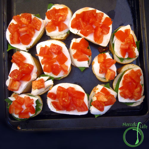 Morsels of Life - Caprese Crostini Step 2 - On top of each bread slice, layer a basil leaf, a slice of mozzarella, and a spoonful of tomatoes. (optional - (1) Bake at 350F for about 5 minutes, until cheese just slightly melty. (2) Drizzle a balsamic reduction on top.)