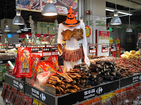 female mannequin dressed in dried meats and wearing a Halloween witch hat