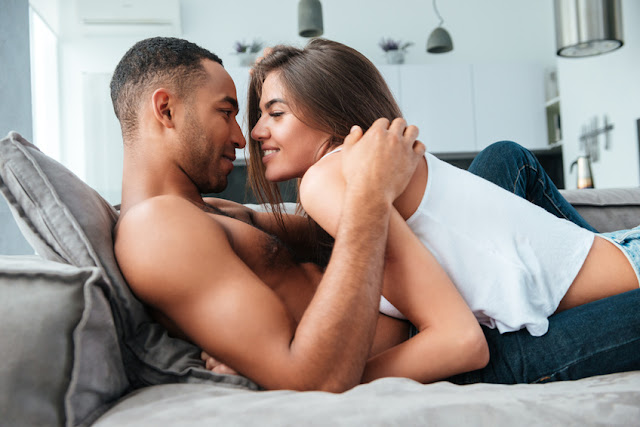 Tender young couple lying and hugging on couch
