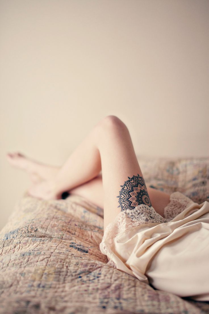 chica acostada en la cama con tatuaje de mndala en el muslo