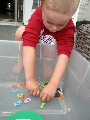 J checking out the bug and numbers in the sensory bin from And Next Comes L
