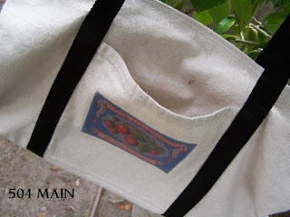 White market tote back with decorative side pocket and black straps.