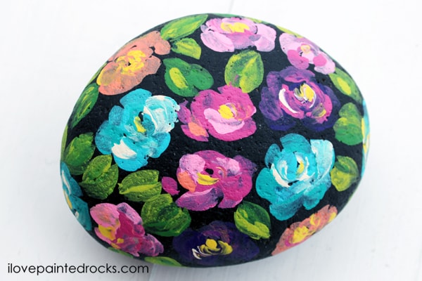 brush stroke flowers painted on a rock with a black background