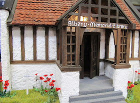 One-twelfth scale miniature arts-and-crafts library with poppies and crosses planted around it.