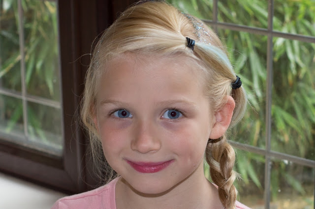 A young girl with pink lips smiling at the camera