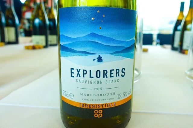 A close up of Explorers Sauvignon Blanc white wine this a person in a canoe and mountains in the background