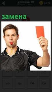 Арбитр поднял красную карточку для замены игрока и свисток держит во рту 