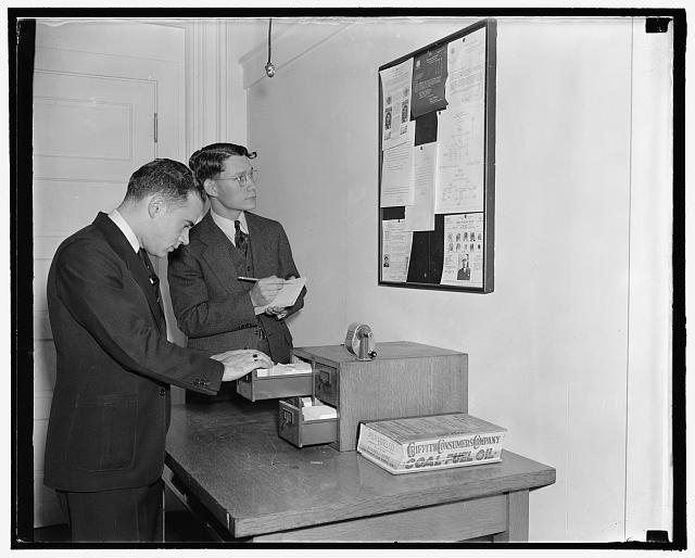 Employees of the Secret Service checking over bulletin board getting latest criminal news, 10/38