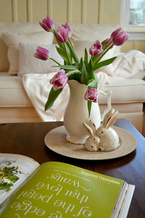 Tulips in a pitcher on a coffee tables with a bunny figurine