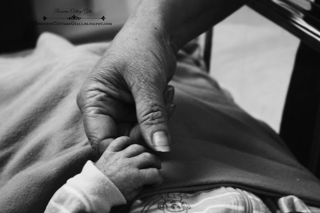 A woman holding the hand of a newborn infant in the hospital by rosevinecottagegirls.com
