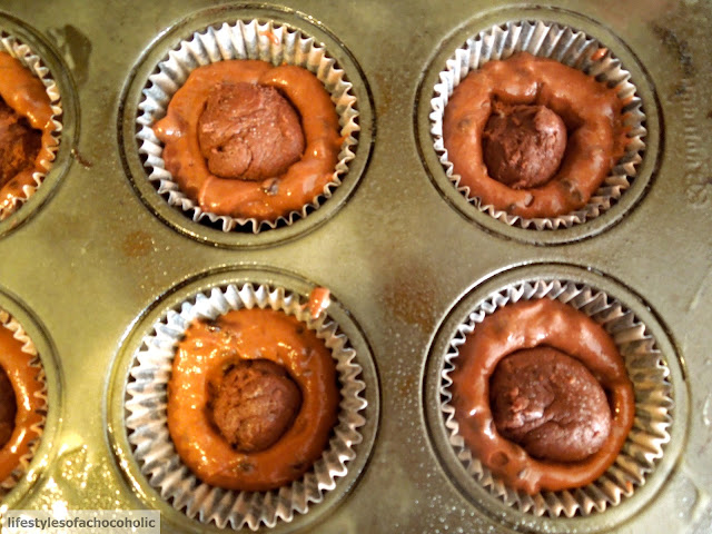 brownie batter stuffed into cupcake batter in a cupcake pan before baking